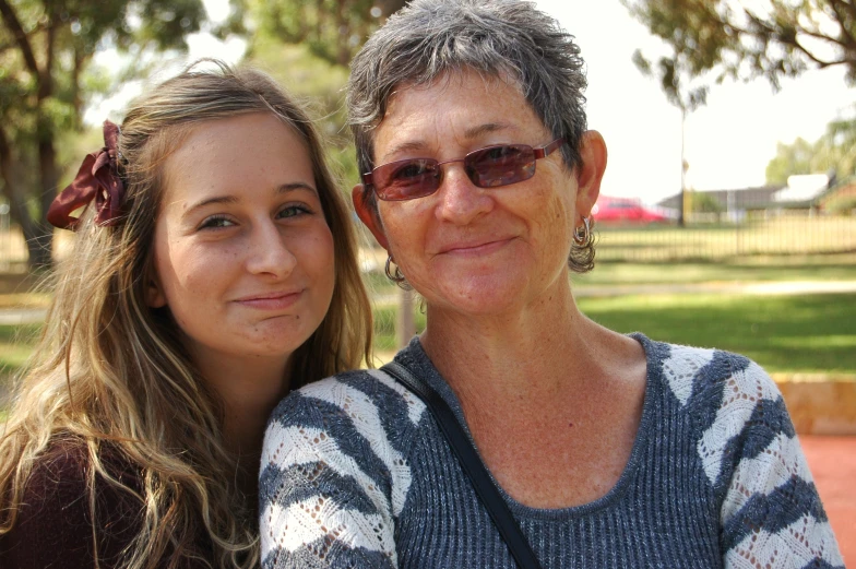 two women standing next to each other in the park