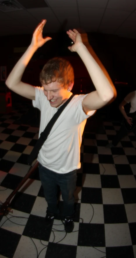 a young man standing in a room with his hands up