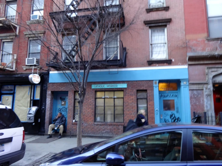 a blue building with a fire escape and a sidewalk corner