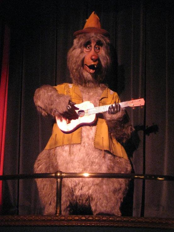 a stuffed animal is dressed in a hat and playing the guitar