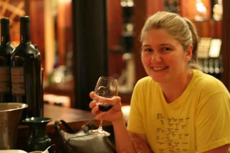 the woman is holding a glass of wine at the bar