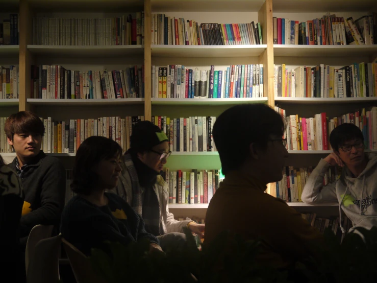 people sitting in a line in front of bookshelves