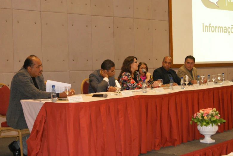 several people sitting at a long table and speaking