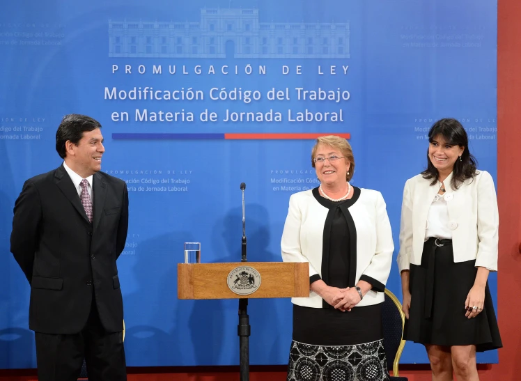 two women stand next to a man at a podium