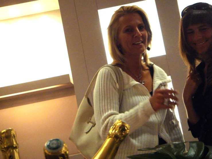 two woman stand holding some champagne and a large glass