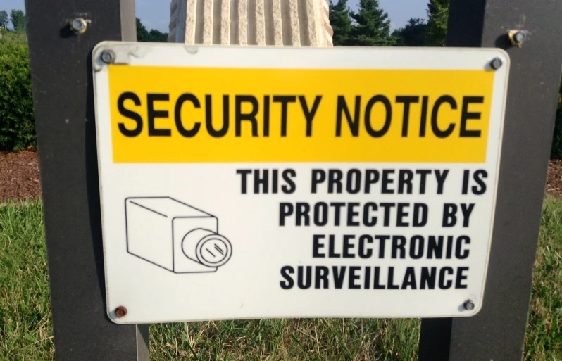 a sign on the side of a fence stating that security notice is protected by electronic surveillance