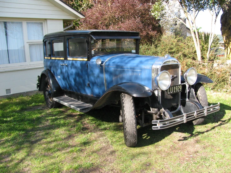 an old fashioned blue pickup truck parked in front of a white house