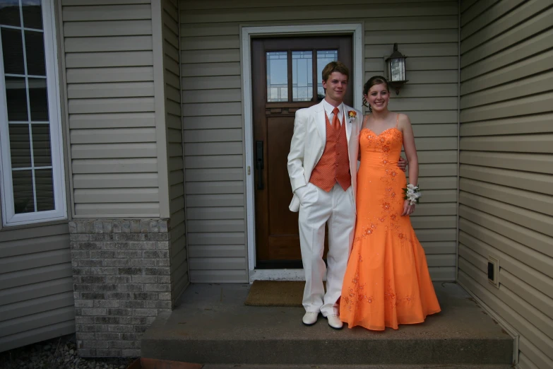 a couple is dressed in orange standing together