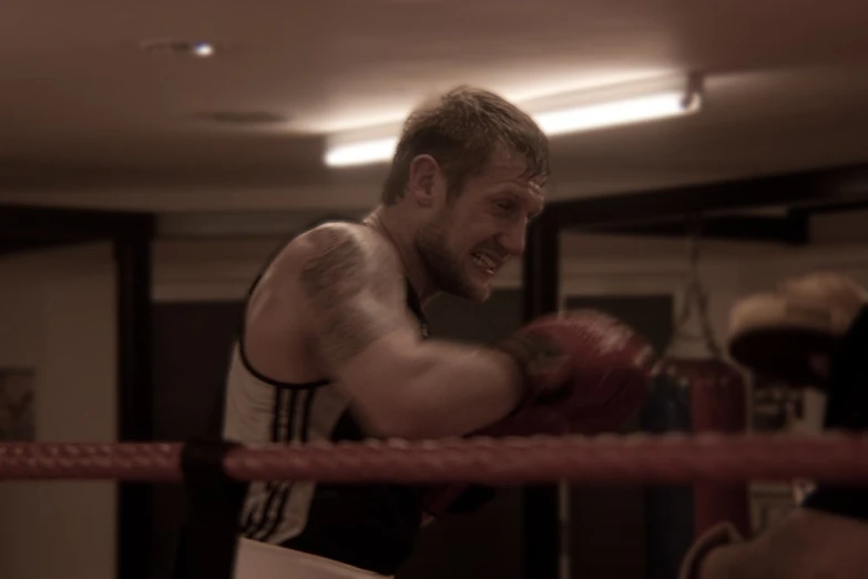 a man is holding up boxing gloves as he looks into a cage