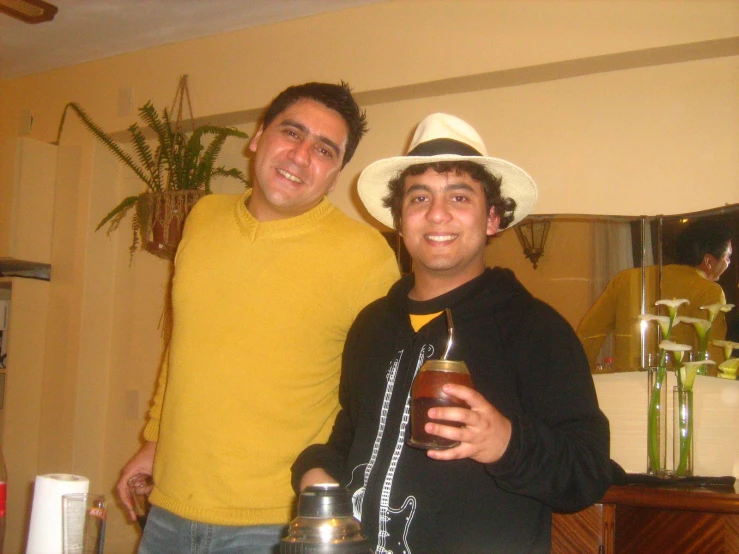 two men pose with drinks on the table