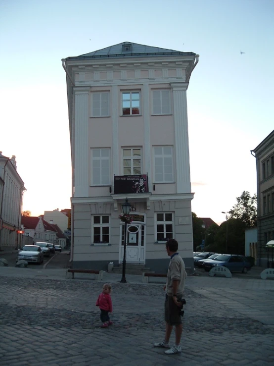 a man is standing in front of a building and two s are running towards it