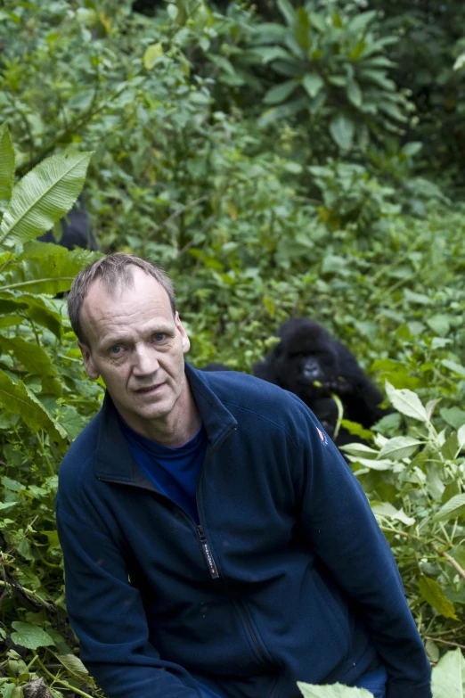 a man in a blue jacket sitting in the woods