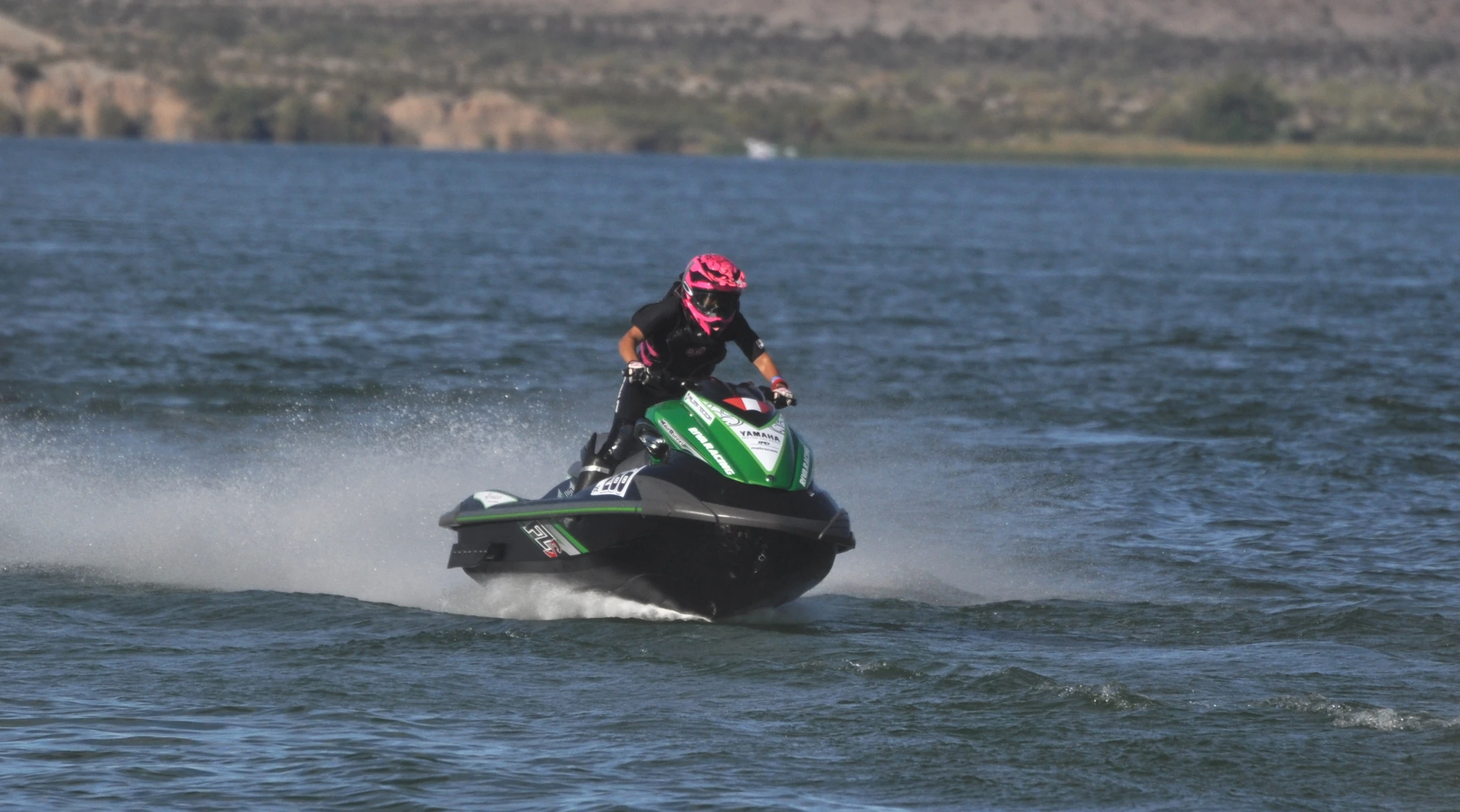 man riding a green jet ski across blue water