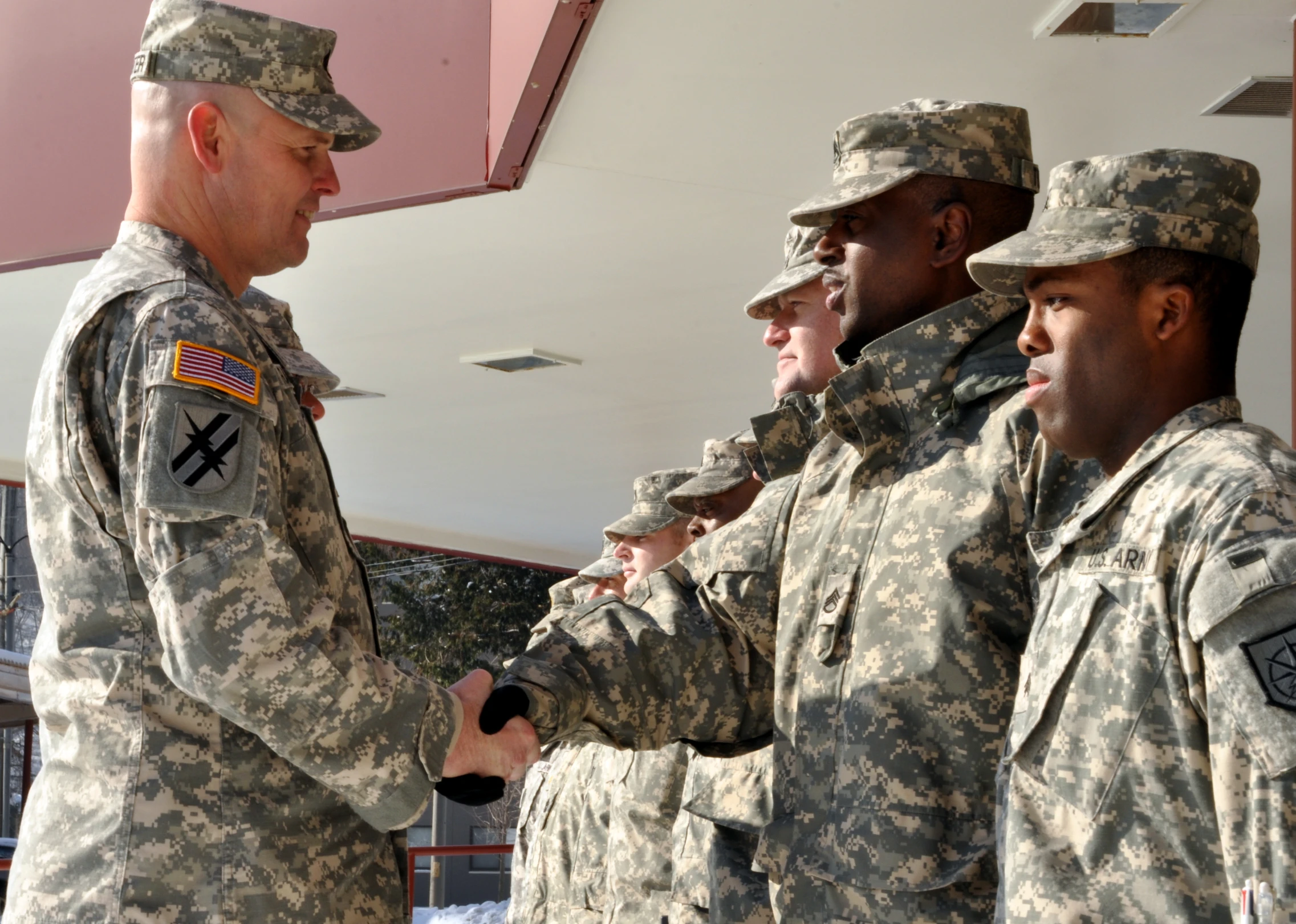 four men in fatigues shaking hands near each other