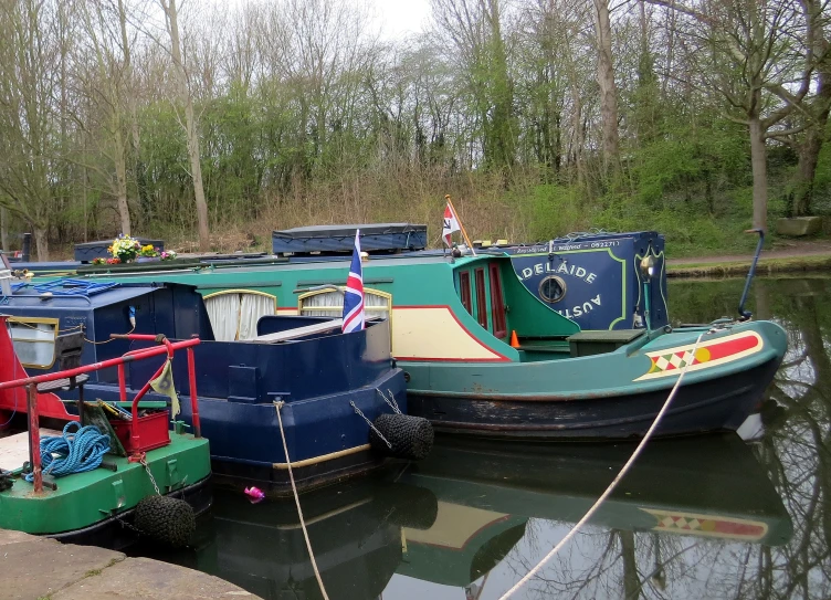 a river filled with three green tugboats next to a lush green forest