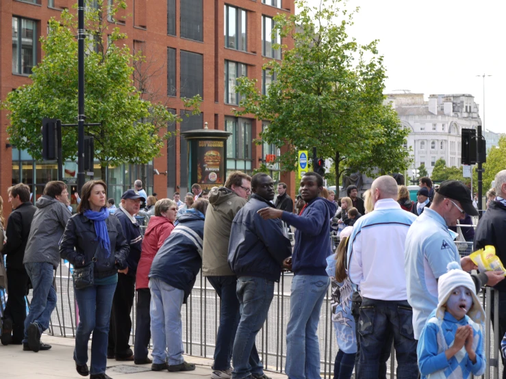 people gathered around a barrier and building by a metal fence