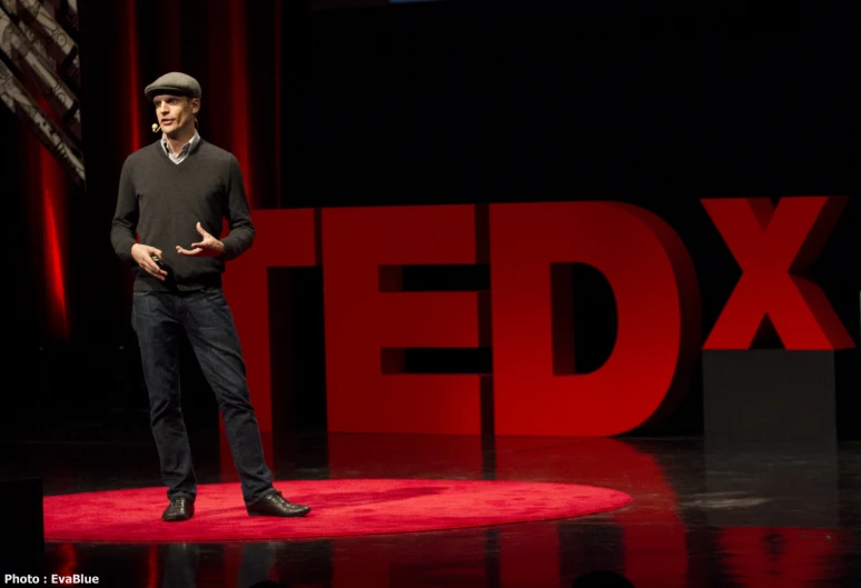 a man standing on a stage talking in front of a ted banner