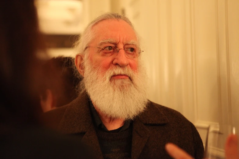 an older man with a beard and glasses standing in front of a mirror