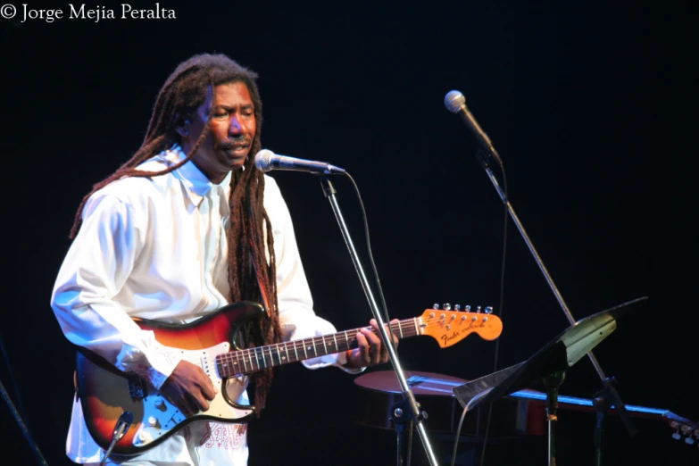 a man with long dreads playing guitar at a concert