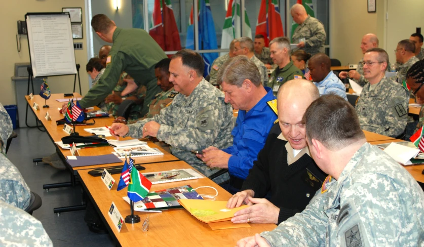 the military men are sitting around the table with books