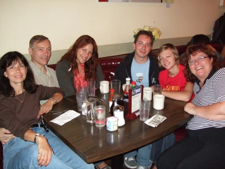 a group of people sitting around a table smiling for the camera