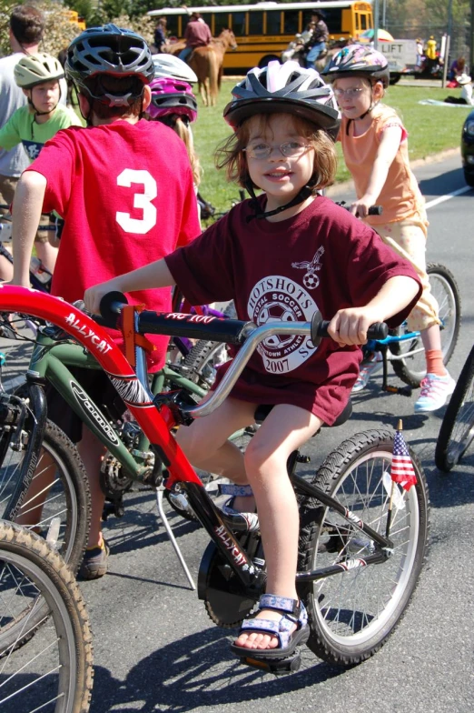 two children in helmets and riding bicycles on the street