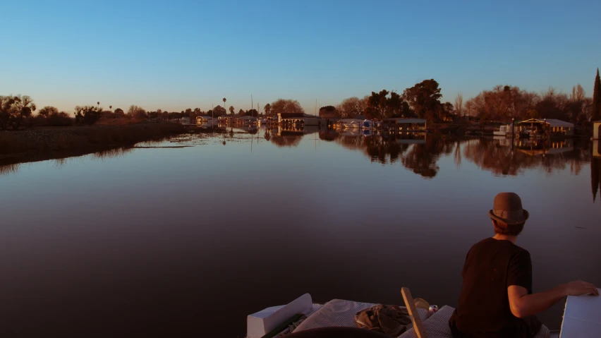 a man in a boat on a river near a body of water