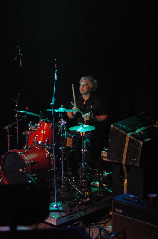 a drummer at a concert is performing in the dark