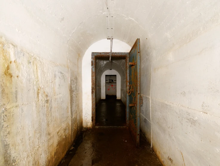 some dark narrow hallway with white walls and peeling paint