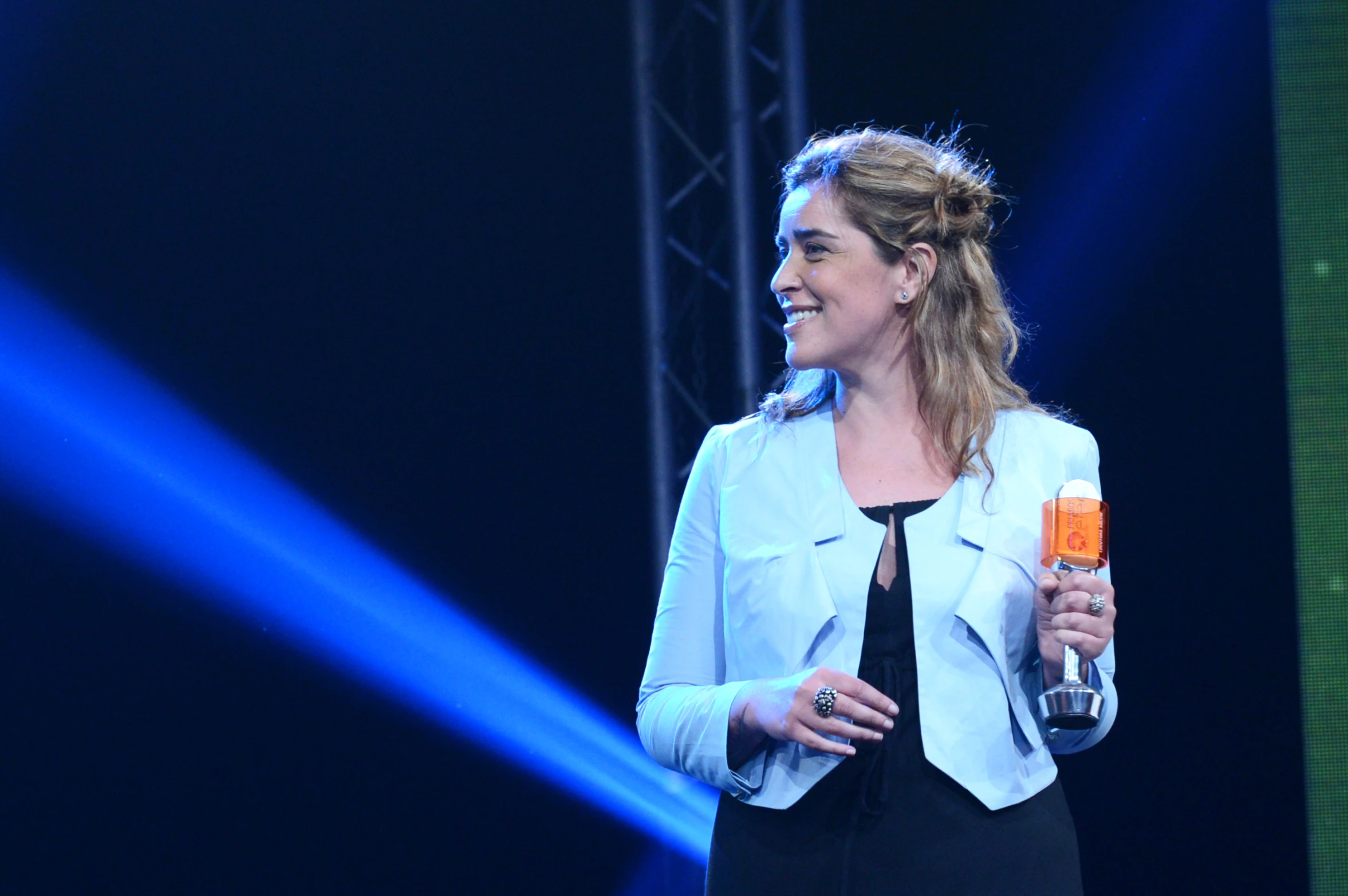 a lady that is standing on a stage holding an orange object