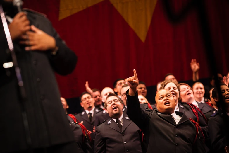 there are many children singing in front of a crowd