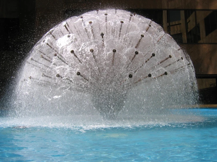 the large water wheel is splashing in the pool