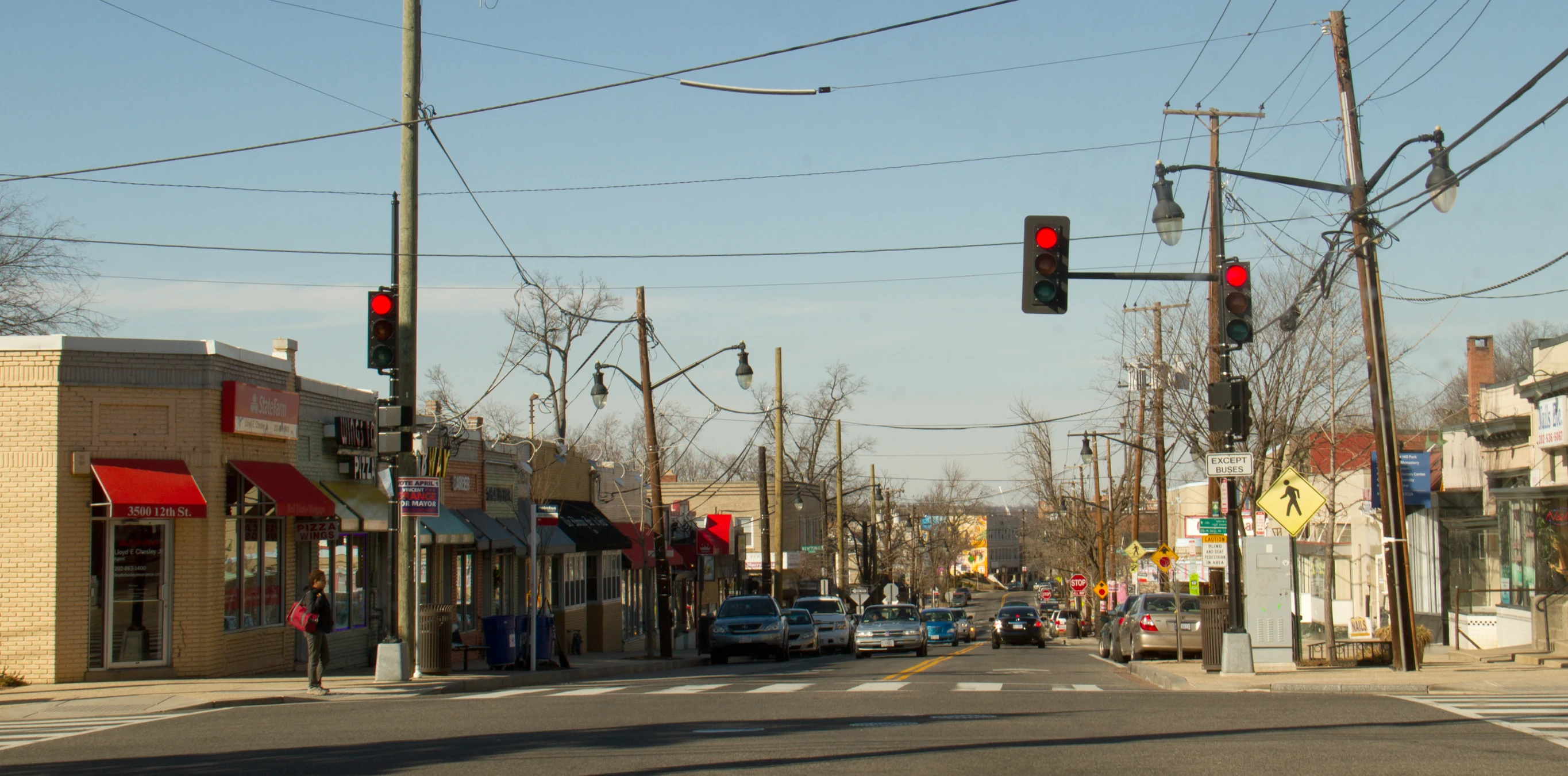 the intersection of a city street is empty and there are cars waiting at red lights