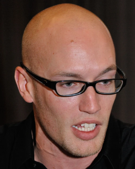 a bald man wearing glasses while looking up