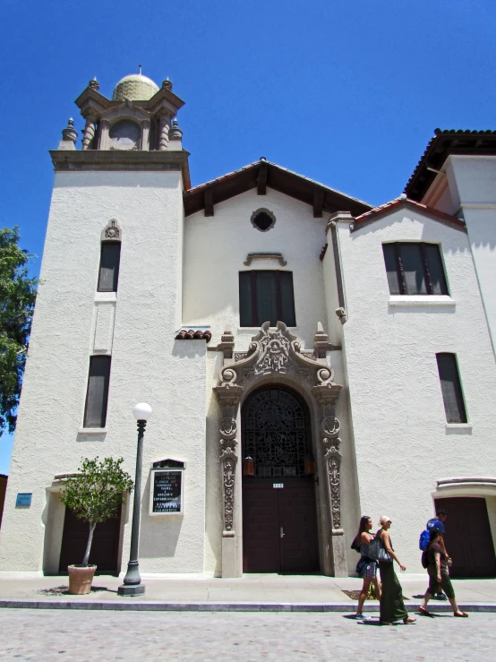 people walk on a cobblestone street near a church