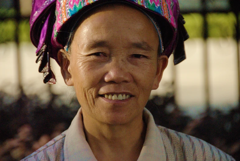 an old woman smiling wearing a colorful hat