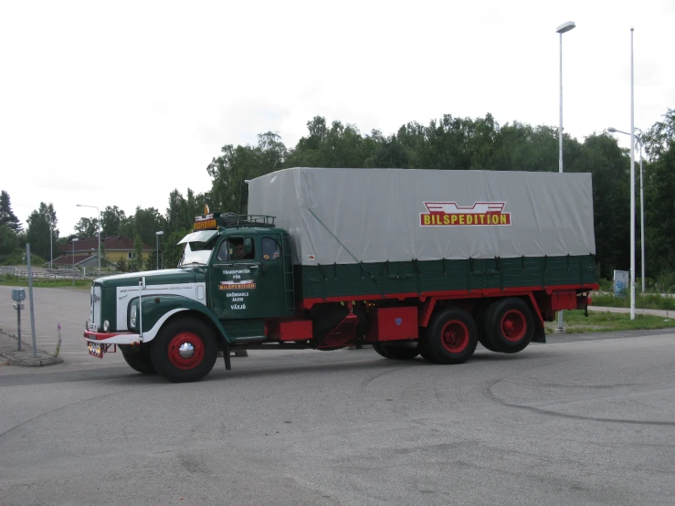 a green and red semi truck traveling down a road