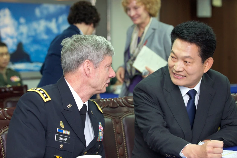 two men in military uniforms sitting down at tables with cups