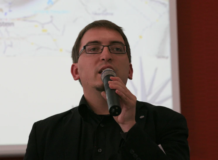 a man in glasses is holding a microphone