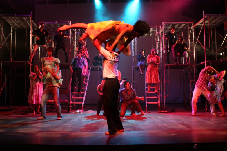 men doing a aerial act on stage with lights coming from behind