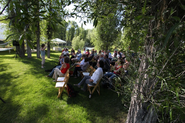 an outdoor wedding under some trees next to the lake