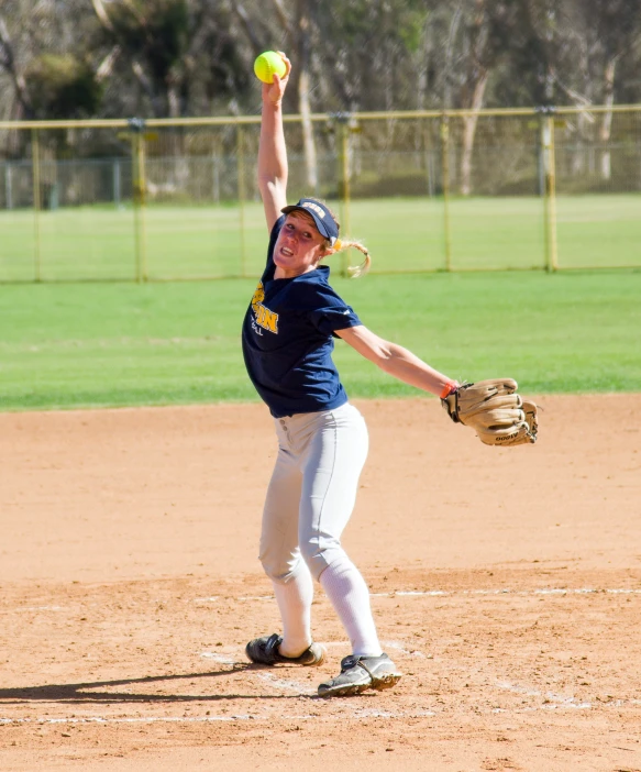 the girl is playing a softball game and throwing it