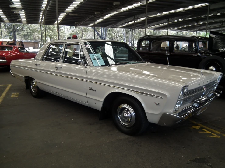 white car parked next to other vehicles in a garage