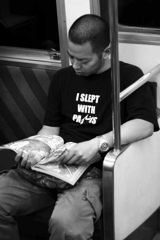 a man sitting down reading a book on the train