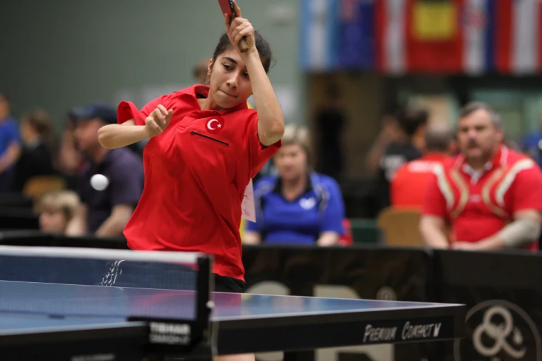 a man in red playing tennis while people look on