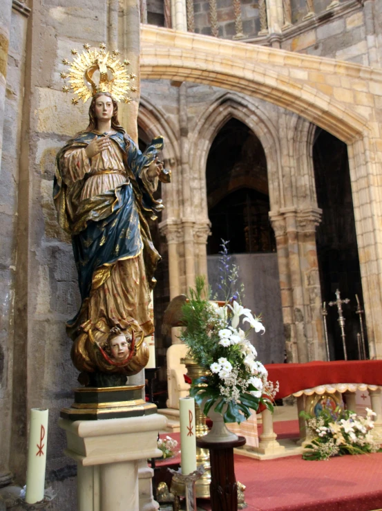 a statue in a stone church that has roses in vases and an open window