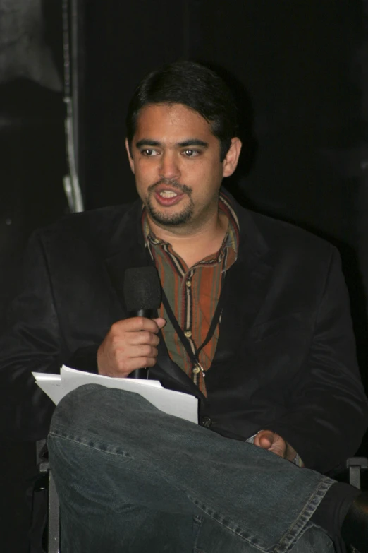 a man with a microphone and in the background sits