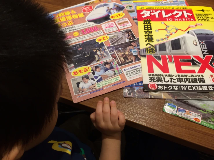 a child sits with magazines, which are about six - year old