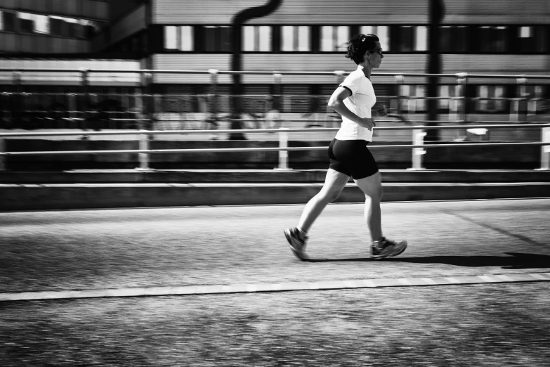 the woman is jogging on the road while wearing sports clothing