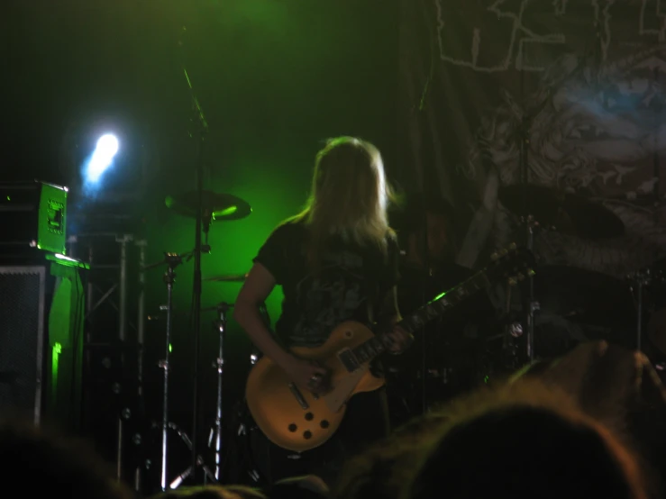 a person playing guitar while another person stands on stage